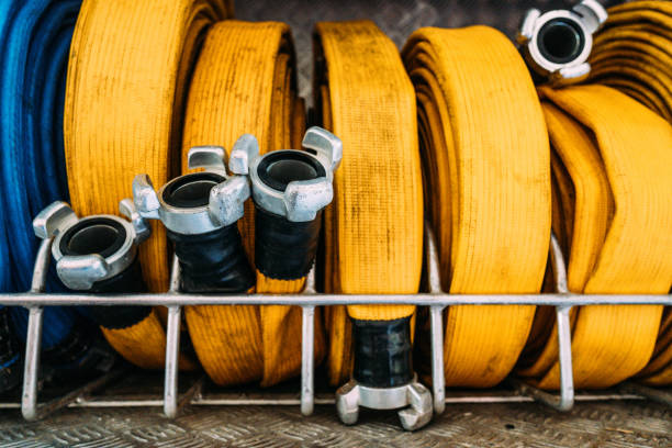 Kit of yellow rolled dirty fire hoses made of high strength materials with metal mandrels on edges on metal shelf in fire truck stock photo