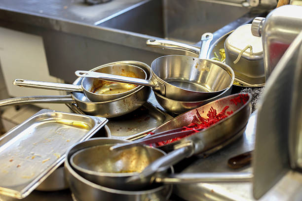 Kitchen in restaurant, sink filled with dirty metal dishes stock photo