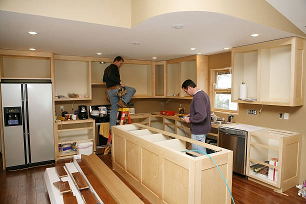 Kitchen Remodel Cabinet maker installing custom made kitchen island and cabinets, while electrician installs in-cabinet lighting. 

Very shallow DOF quickly drops off to nice soft focus. home addition stock pictures, royalty-free photos & images