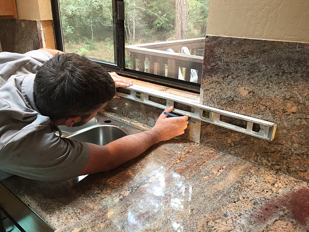A man leveling the counter top of a kitchen sink so as to install a tap