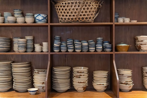 Kitchenware with dishware keeping on kitchen wooden shelving.Traditional Vietnamese blue porcelain with plates and bowls in Southeast Asia in Vietnam. Handmade souvenirs of crockery and tableware.