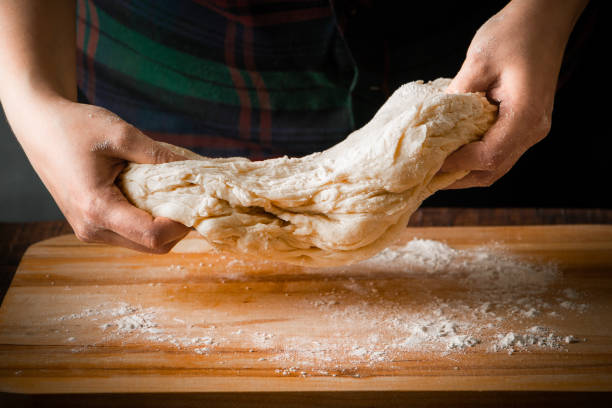 Kneading the dough on a wooden board on a dark background stock photo