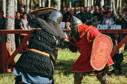 Reconstruction of medieval tournaments of knights. Knights in armor and helmets, fighting with swords and shields in the arena. Festival of historical clubs. Bishkek, Kyrgyzstan - October 13, 2019