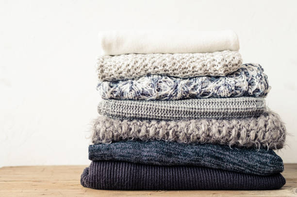 Knitted wool sweaters Pile of knitted woolen sweaters. Monochrome gradient shades grey white black colors clothes with different knitting patterns folded in stack. Warm cozy winter autumn knitwear concept. Copy space. blanket stock pictures, royalty-free photos & images