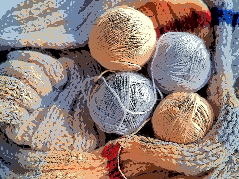 Knitting a scarf or sweater from gray, beige and orange yarns. Balls of woolen and acrylic threads. Knitting as a hobby. Accessories, knitting needles, crochet hooks