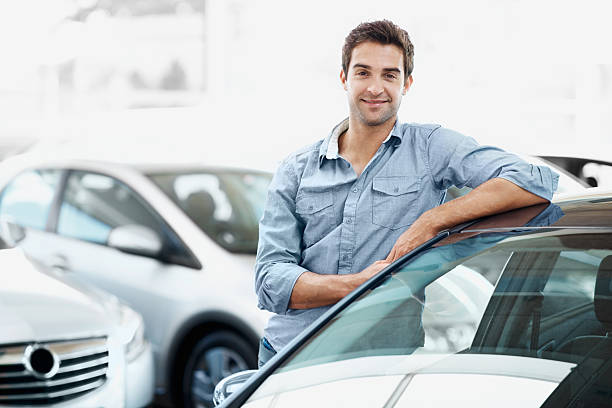 I know exactly which model I'm looking for Smiling young guy standing alongside a car and leaning against it leaning stock pictures, royalty-free photos & images