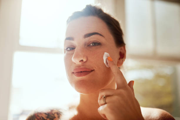 I know what makes my skin glow Shot of an attractive young woman applying moisturiser during her morning beauty routine beautiful voluptuous women stock pictures, royalty-free photos & images