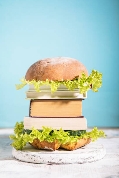 Knowledge fast food concept represented by burger with books on blue  background stock photo