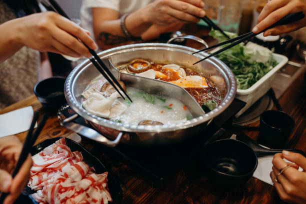 Korean hot pot meal. Hands taking food with chopsticks. stock photo