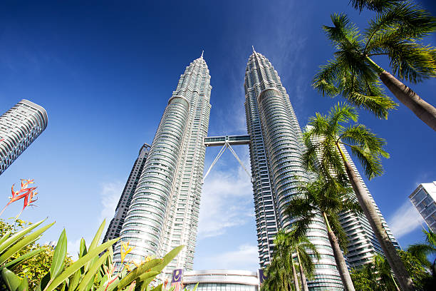 Kuala Lumpur's Petronas twin towers against blue sky Low angle view of impressive Petronas twin towers in Kuala Lumpur. More files of Petronas on port including night shots. petronas towers stock pictures, royalty-free photos & images