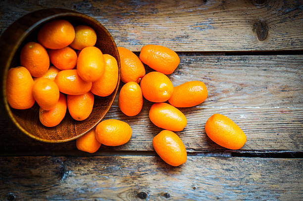 Kumquat in a bowl on rustic wooden table Kumquat in a bowl on rustic wooden table kumquat stock pictures, royalty-free photos & images