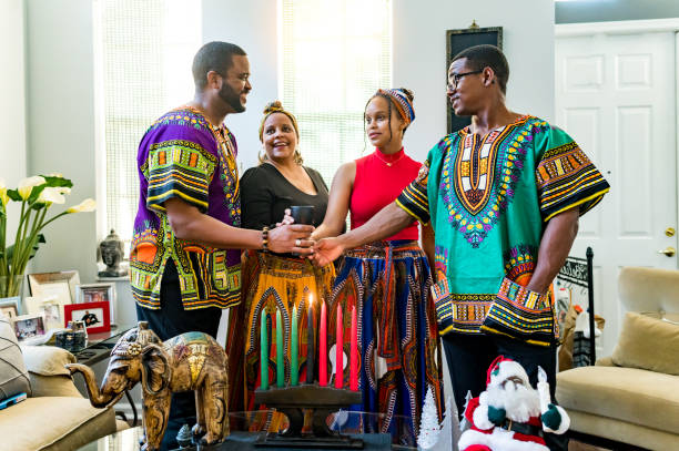 Kwanzaa celebration, African American family holding the unity cup together at home with kinara stock photo