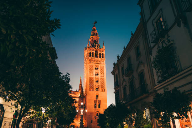 La Giralda at night La Giralda tower at night as seen from a street nearby. seville cathedral stock pictures, royalty-free photos & images