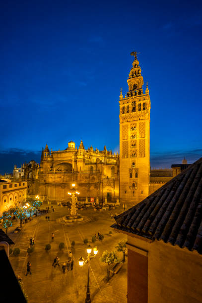 La Giralda illuminated at night from the rooftops La Giralda illuminated at night from the rooftops seville cathedral stock pictures, royalty-free photos & images