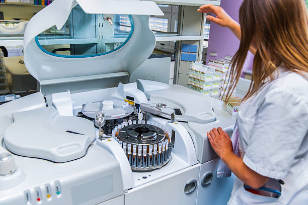 Lab scientist placing test tubes with blood samples in centrifuge stock photo