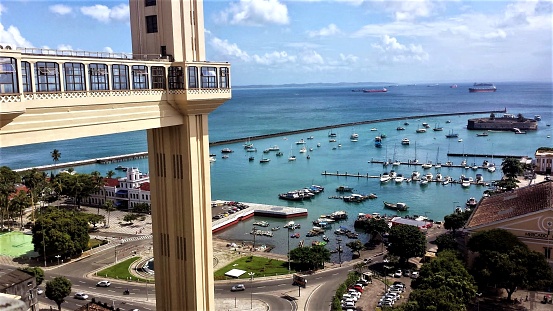 View of the Lacerda Elevator and the Todos-os-Santos Bay in the background. Elevador Lacerda is a public transport system in the city of Salvador, capital of the Brazilian state of Bahia. It is the world's first urban elevator. On December 8, 1873, when the first tower opened, it was the tallest elevator in the world at 63 meters. The current structure, from 1930, is 72 meters high. It transports people between Praça Cairu, in Cidade Baixa, and Praça Tomé de Sousa, in Cidade Alta. It is one of the main tourist attractions and postcard of the city. From the top of its towers, there is a view of the Todos-os-Santos Bay, the Mercado Modelo and, in the background, the Forte de São Marcelo.
