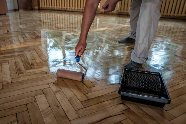 Lacquering wood floors. Worker uses a roller to coating floors. stock photo