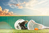 istock A lacrosse stick, ball and helmet sitting on a synthetic grass turf with sunbeams 1129367194