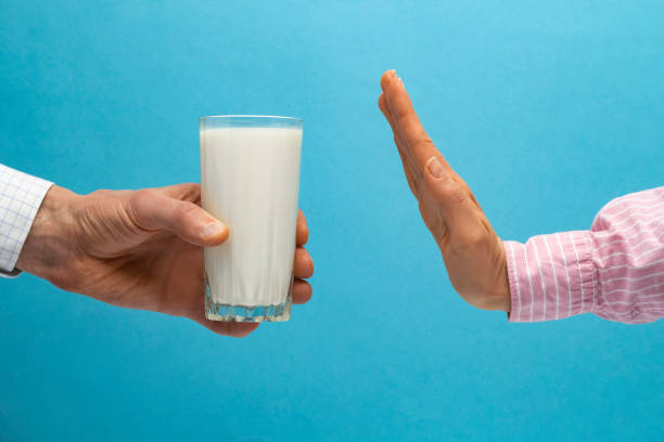 Lactose intolerance. Glass of milk and hand showing stop. stock photo