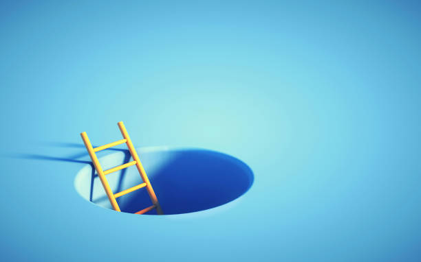 Ladder rises up from a hole in the ground. stock photo