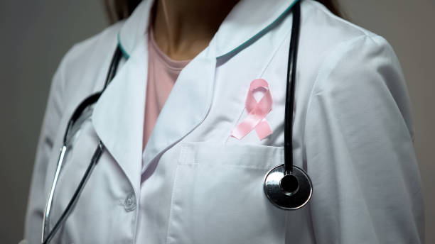 docteur de dame attachant le ruban rose au costume médical blanc, sensibilisation de cancer du sein - faune photos et images de collection