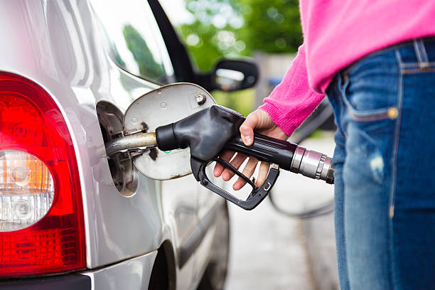 Lady pumping gasoline fuel in car at gas station. stock photo