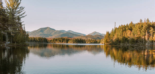 Lake during sunset/golden hour over Boreas Ponds in the Adirondacks Kayaking in Boreas Ponds in the Adirondacks on a glassy lake with Mount Marcy and the high peaks in the background as the sun is setting"n adirondack state park stock pictures, royalty-free photos & images