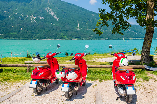 Three red vespas overlooking the Lake Santa Croce, a semi-natural lake in the province of Belluno