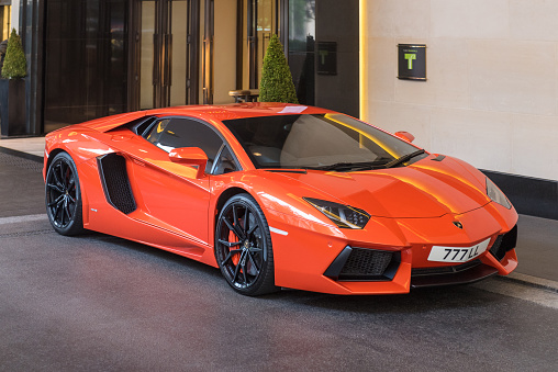 London, England, UK - 19th June 2016: An orange Lamborghini Aventador parked outside the InterContinental London Park Lane hotel in Mayfair. The Aventador is a mid-engined sports car produced by Italian car manufacturer Lamborghini.