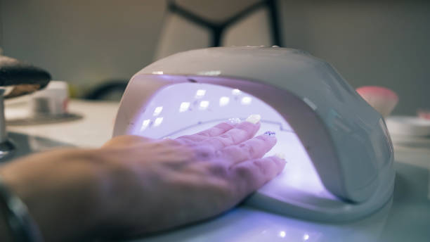 UV lamp gel polish manicure process. Salon procedure. The master coats the client's nails with a varnish. UV lamp gel polish manicure process. Salon procedure. The master coats the client's nails with a varnish. gel nail polish stock pictures, royalty-free photos & images