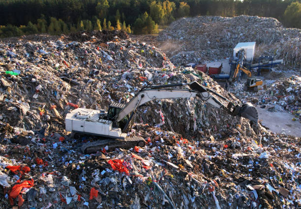 Landfill with Construction and Demolition waste (CDW). Trash disposal for recycling and re-use. Excavator working on industrial landfill. stock photo