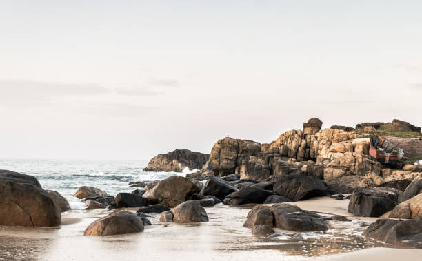 Landscape photo of huge rocks on the beach with rising sun stock photo
