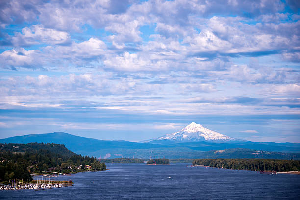 Landscape with Columbia river and Mount Hood Panorama of Columbia River with forest banks and the marina, with a wavy blue water and the mountains on the horizon, which sticks out above the snow-covered Mount Hood, resting against a cloudy blue sky. columbia river gorge stock pictures, royalty-free photos & images