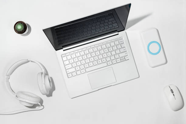 Laptop 13.3 inches, white powerbank, white headphones, wireless mouse and cactus on a white background. Flat lay with copy space stock photo