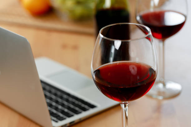 laptop and glass of red wine on wooden kitchen table - balcão computador imagens e fotografias de stock