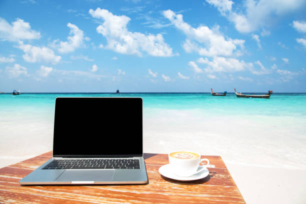 laptopcomputer en koffie kopje op de tafel aan zee - branding bureau stockfoto's en -beelden