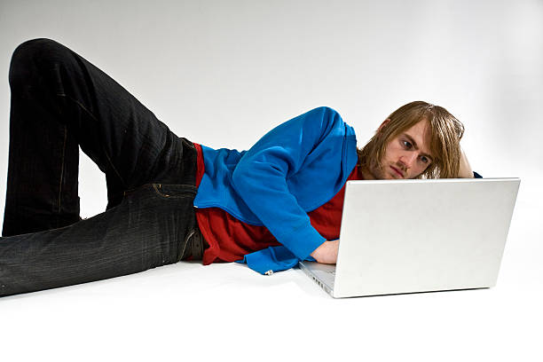 laptop man lying down using computer stock photo