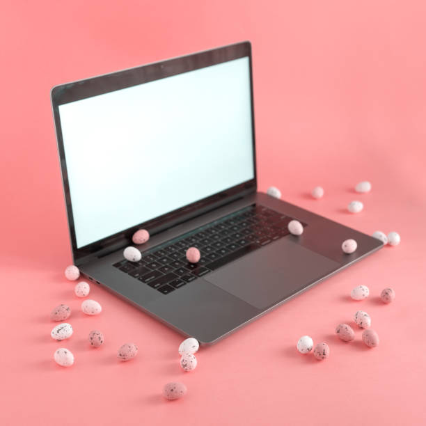 Laptop with blank screen and many small freckled Easter eggs scattered around stock photo
