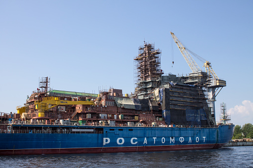 large cargo ship with a loading crane moored in the port on the Neva River on a sunny summer day close-up in Saint-Petersburg