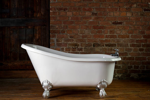 A large claw foot bathtub on a wooden floor stock photo