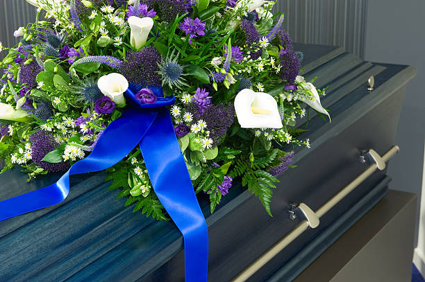 A large coffin in a morgue topped with flowers stock photo
