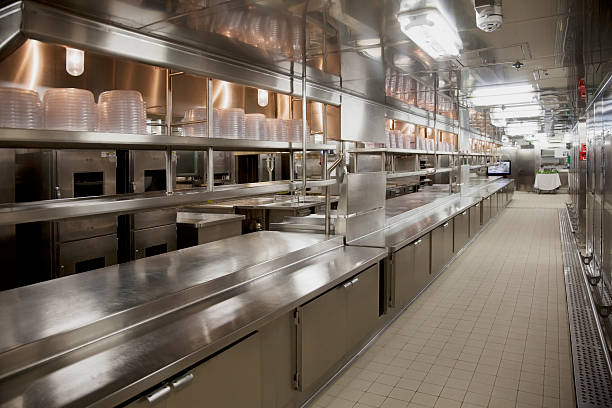 Large commercial kitchen Stainless steel modern commercial kitchen. Clean polished worktops, cupboards, shelves and plate covers. commercial kitchen stock pictures, royalty-free photos & images