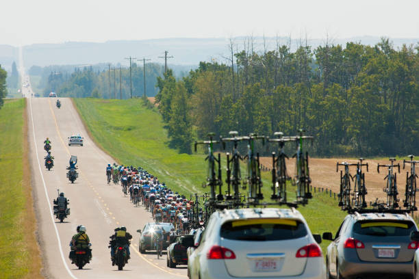 un gran grupo de corredores de bicicletas de hombre viajar juntos en un pelotón durante una carrera de bicicleta de carretera profesional. - peloton fotografías e imágenes de stock