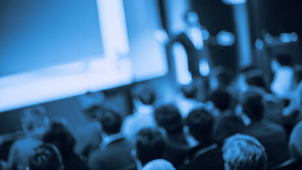 Large Group of People Listening to a Presentation Defocused shot of crowd in the lecture hall. Purposely blurred with a lens and toned. entertainment event stock pictures, royalty-free photos & images