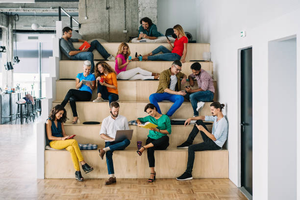 Large group of people networking in a loft office Large group of people texting, surfing and reading in a loft apartment large group of people stock pictures, royalty-free photos & images