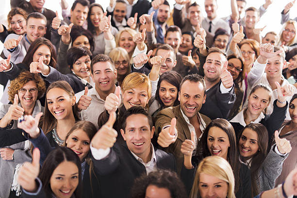 Large group of people smiling and giving thumbs up stock photo