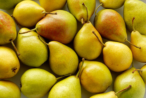 A large pile of whole pears with a stem stock photo