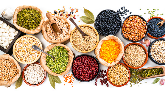Food Backgrounds: large variety of dried beans, legumes and cereals shot from above on white background. The composition includes green, yellow and brown lentils, chick-peas, black beans, Pinto beans, Kidney beans, fava beans, mung beans, white beans and soy beans among others. High resolution 35,5Mp studio digital capture taken with SONY A7rII and Zeiss Batis 40mm F2.0 CF lens