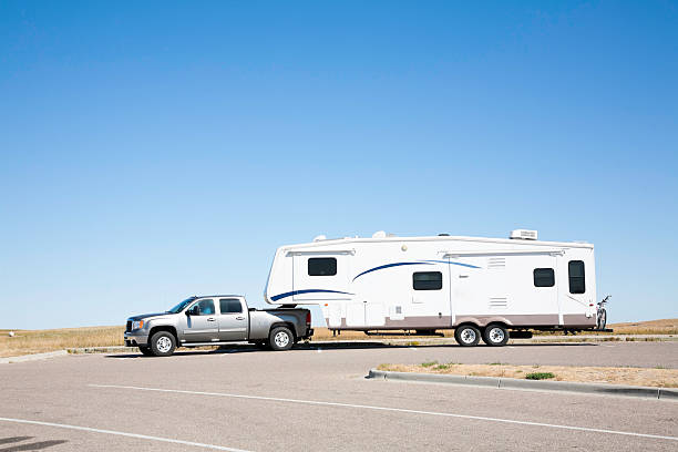 Large white RV trailer hitched to a double cab gray truck stock photo