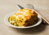 Lasagna with pumpkin, spinach and turkey meat on brown background.